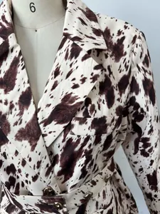 Détail en gros plan montrant le revers et l'imprimé vache marron d'un blazer long