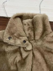Détail d'un gilet en fausse fourrure marron à col montant avec des boutons pressions fins
