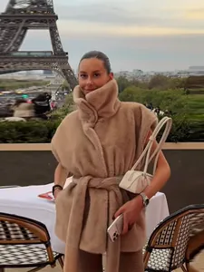 Vue lifestyle d'un gilet en fausse fourrure camel avec col haut et ceinture à la taille