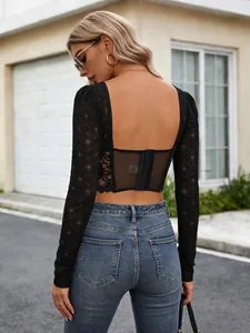 Détail d'un crop top noir en dentelle et mesh à manches longues avec agrafes au dos