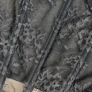 Primo piano del delicato pizzo floreale nero e della trama del tessuto a rete velata