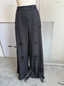 Detailansicht der schwarzen Paillettenstickerei auf der nadelstreifen weiten Hose für Damen