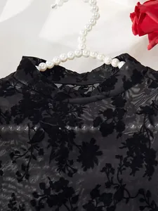 Close-up view of black mesh flocked bodysuit lingerie with floral pattern on a pearl hanger