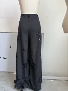 Detail der Nadelstreifenhose mit schwarzen Paillettenstickereien auf einer Schaufensterpuppe.