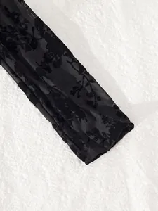 Close-up of black sheer mesh sleeve featuring a delicate floral flocking pattern