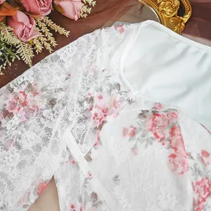 Close-up detail of white lace bodysuit with romantic pink floral print and sheer texture