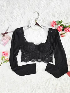 Détail de la texture de dentelle florale sur un haut corset noir à manches longues