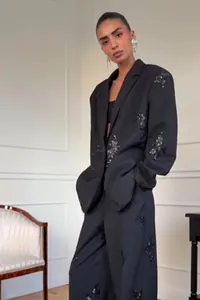 Detailed view of women's black suit set with sequin floral embroidery and straight-leg trousers