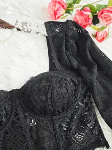 Détail du haut en dentelle noire à manches longues avec maille ajourée et design transparent.