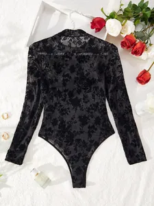 Detailed view of back of black mesh bodysuit with floral flocking patterns