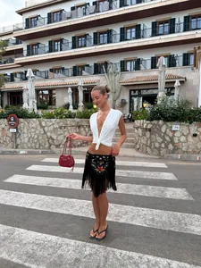 Minifalda bohemia con bordado floral y flecos en una modelo en entorno de resort