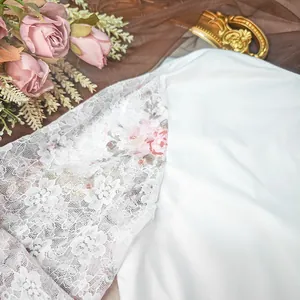 Macro view of a white bodysuit featuring delicate lace sleeves with pink floral print