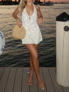 Detail of white sequined halter top worn by model in a coastal setting at sunset