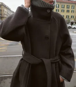 Dettaglio di un elegante cappotto di lana antracite con collo alto e cintura.