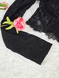 Gros plan sur la manche d'un haut en dentelle noire avec motifs de diamants et bordure