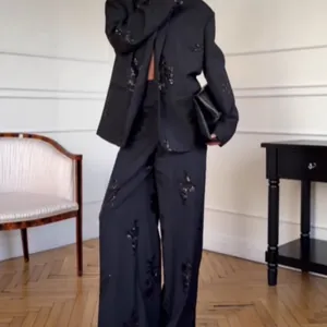 Detailansicht eines schwarzen Blazers und einer weit geschnittenen Hose mit Paillettenstickerei