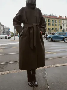 Dettaglio di un lungo cappotto in lana marrone scuro con cintura e collo alto d'élite