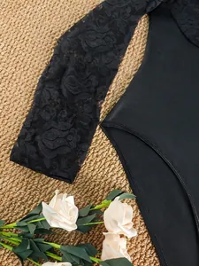 Detailansicht eines Bodysuits mit floralen Spitzenärmeln und schwarzem Stoff
