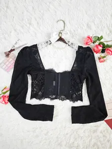 Détail d'un haut court noir en dentelle à manches longues avec motifs transparents