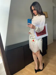 Selfie de espejo de una falda cruzada étnica blanca con bordado floral y detalles de flecos largos.