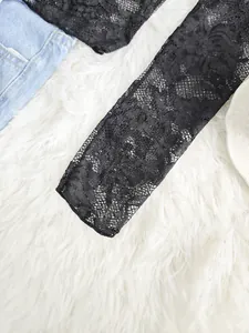Détail rapproché d'une manche en dentelle florale noire sur fond de fausse fourrure.