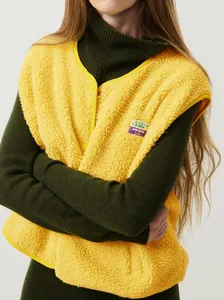 Gilet en polaire jaune court avec fermeture à boutons et détail de l'écusson sur le buste