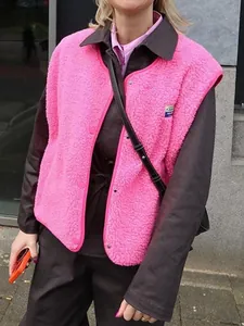 Gros plan d'un gilet en polaire rose vif avec boutons-pression et détail de l'écusson