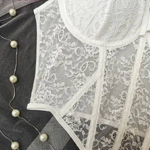 Macro detail of intricate white floral lace and structural boning on a corset top.
