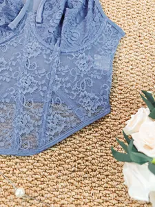 Close-up detail of blue lace corset top with elegant floral patterns and boning support.
