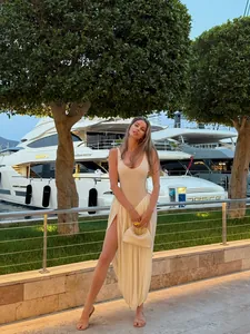 Elegant cream pleated maxi dress with high slit shown in a luxury outdoor yacht setting
