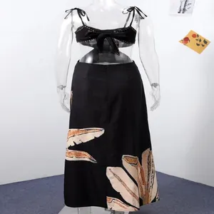Back view of a black tropical print maxi dress with cut-out waist and bow detail