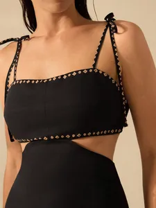 Close-up detail of black waist-baring dress featuring tie-shoulder straps and embroidery