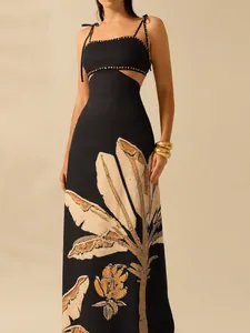 Detail view of elegant black maxi dress with waist cut-outs and palm leaf print