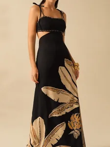 Close-up of black cut-out dress featuring large beige floral and leaf patterns