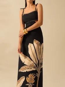 Detailed view of the black resort maxi dress featuring a waist cutout and leaf print