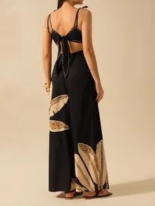 Back view of black backless maxi dress with tropical leaf print and tie detail