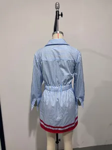 Detail view of a blue and white striped shirt dress with red hem on a mannequin.