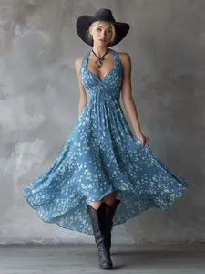 Model wearing a bohemian blue floral halter dress with high-low hem against gray wall
