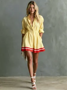 Model wearing a yellow striped shirt dress with red hem detail and side pockets