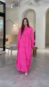 Robe longue rose à volants élégante avec col à nœud et manches longues dans un café chic