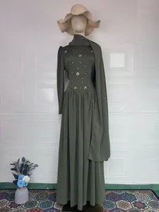 Green modest long-sleeve dress on mannequin with matching hijab and straw hat