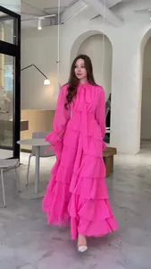 Robe longue à volants magenta avec col noué dans un décor intérieur minimaliste