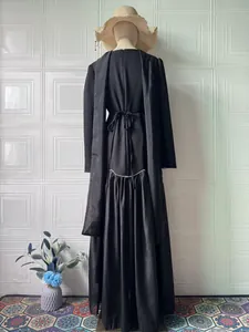 Back view of elegant black long-sleeved maxi dress with waist tie and pleated skirt detail