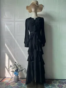 Detailed view of an elegant black tiered maxi dress featuring ruffles and long sleeves
