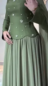 Close-up detail of olive green slim-fit dress with floral embroidery and pleated skirt