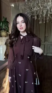 Detail of a brown French vintage long-sleeved dress with pleated bodice and bow accents.