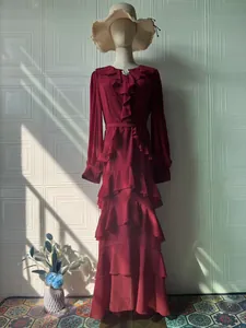 Detailed close-up showing the ruffled layers and elegant brooch of this burgundy maxi dress.