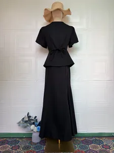 Back view of an elegant black two-piece skirt set on a mannequin with a bow detail.