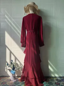 Back view of an elegant burgundy long-sleeved maxi dress with ruffled hem and waist belt