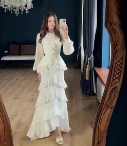 Detailed view of an elegant white ruffled maxi dress with long sleeves in a luxury room